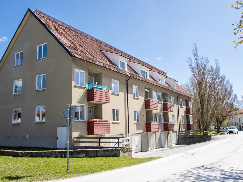 Ljusgult bostadshus med röda balkonger storgatan i Slite. Framför huset är det nedfart till garage och en väg.