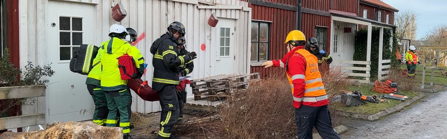 Blåljuspersonal övar utanför i ett hus som ska rivas. 