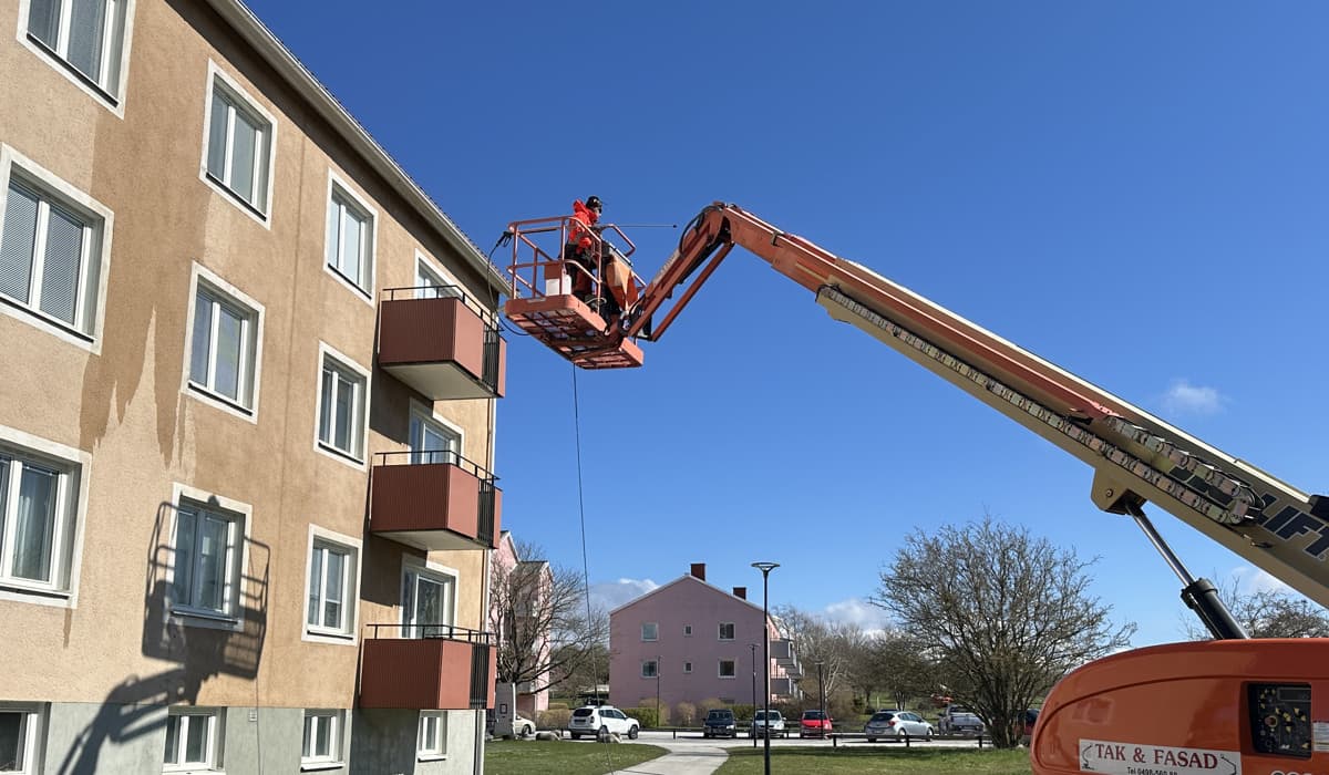 Person på maskin som på hög höjd tvättar fasaden på ett av GotlandsHems bostadshus.