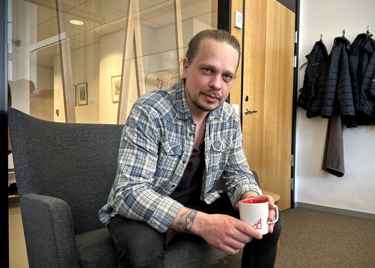 En man sitter i en soffa i kontorsmiljö. 