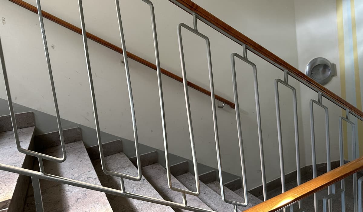 Ett konstnärligt trappräcke i en portuppgång med handtag i trä.