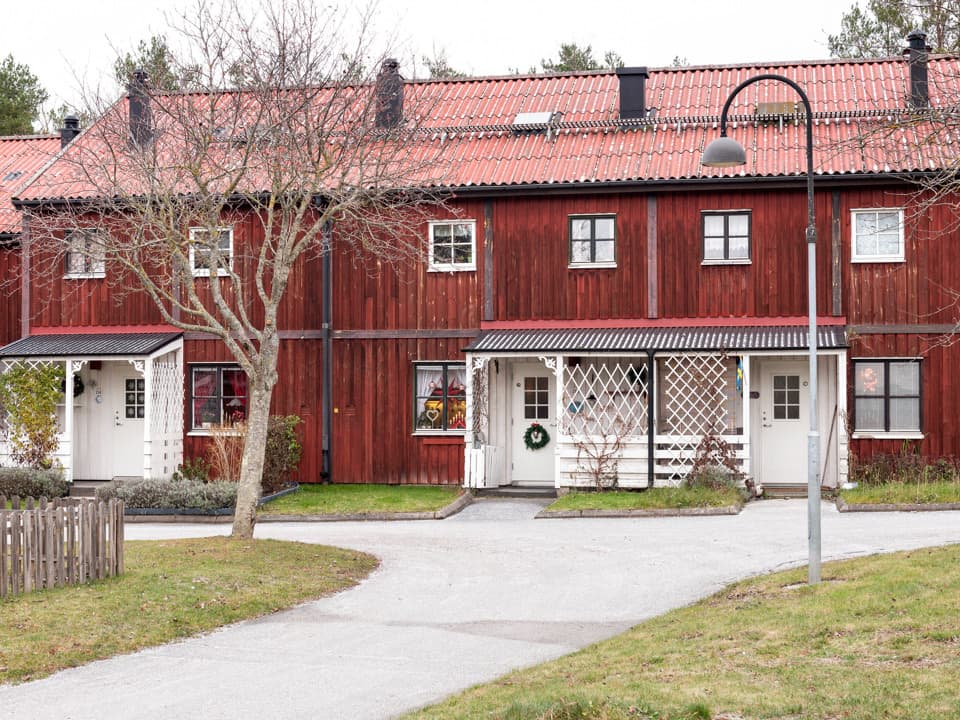 Radhus med röd träfasad och vita entréer. Kvarteret Riggen i Gråbo en mulen decemberdag.
