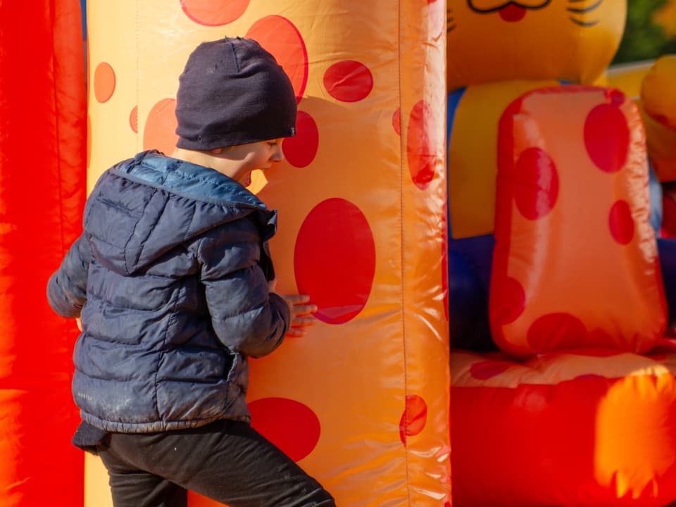 En pojke leker i en orange och röd hoppborg.