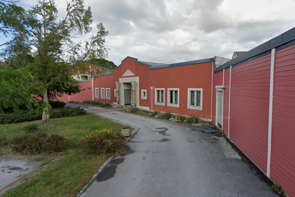 En röd byggnad som ligger bredvid ett stort träd.