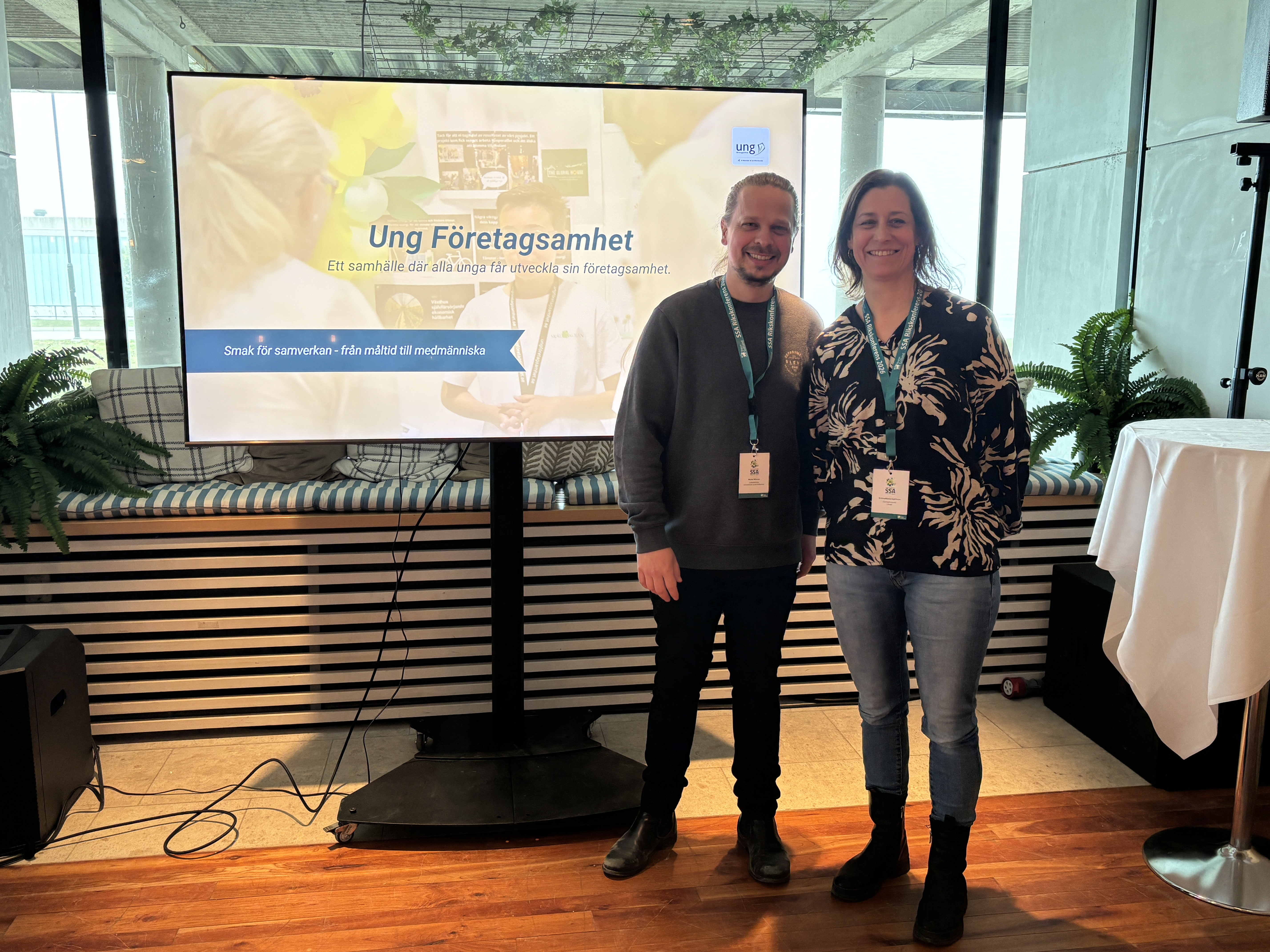 Två personer som står framför en storbildsskärm.