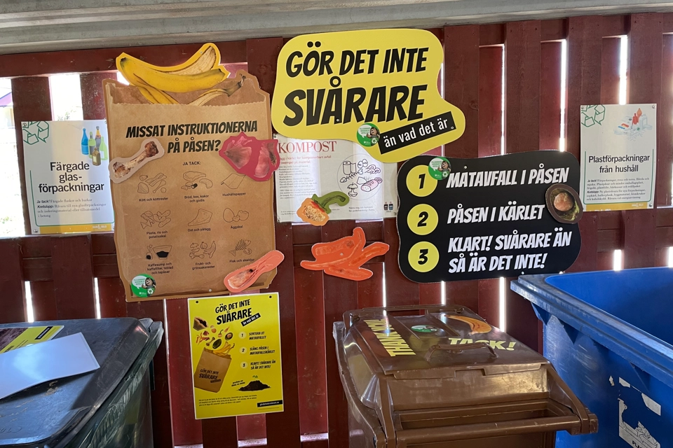 Kampanj för "Gör det inte svårare" inne i soprum. På bild syns posters, tips och sopkärl.