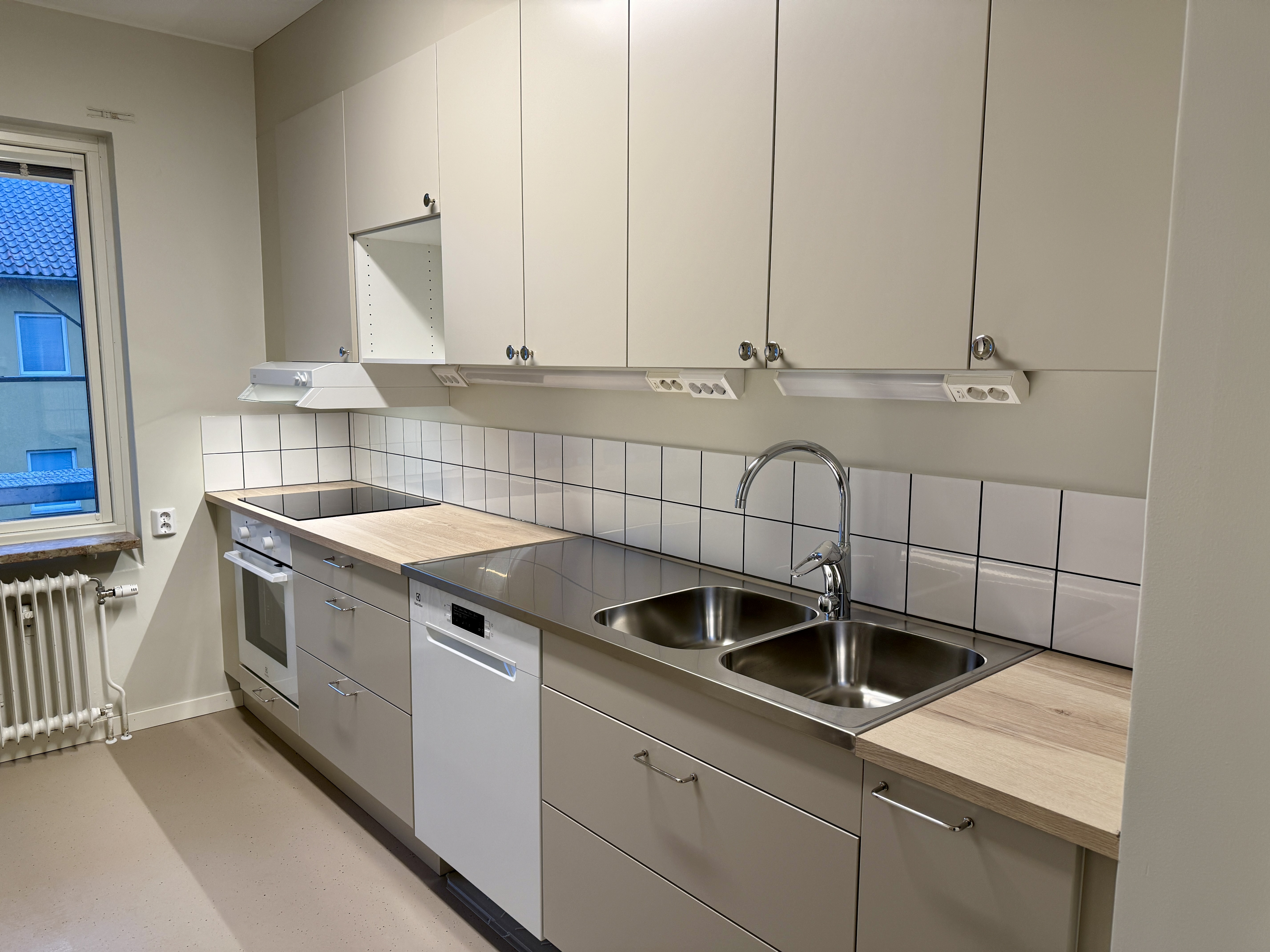 Ett nyrenoverat kök med beigea lådfronter och köksluckor. Ser ser färdigt ut att flytta in i. 