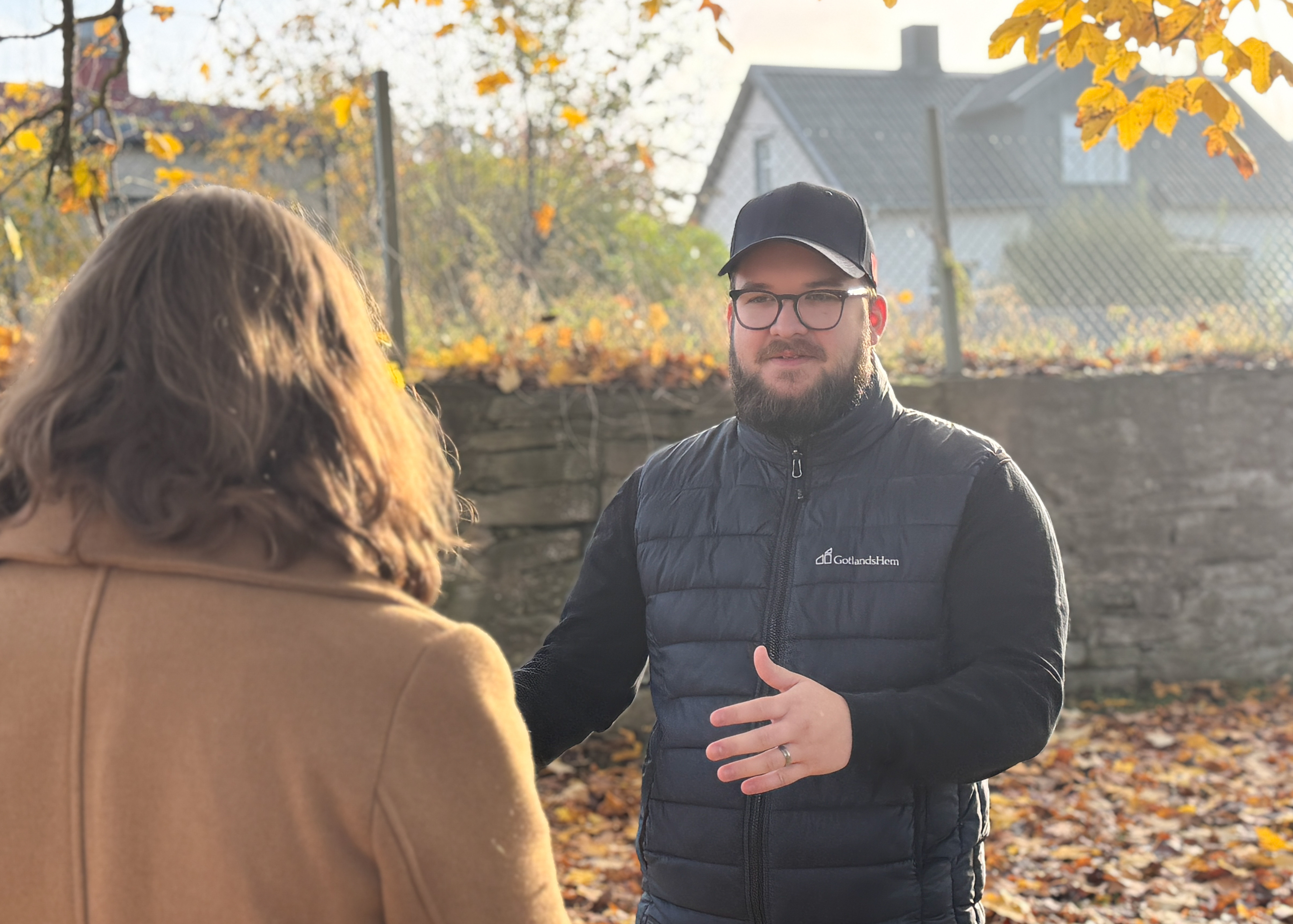 En man med skägg pratar med en kvinna ute en höstdag.