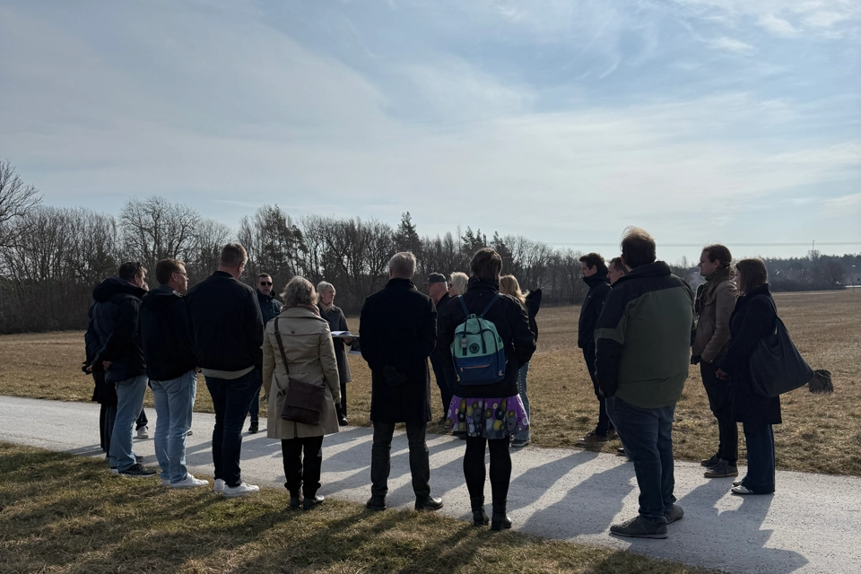 En grupp människor som står på en väg bredvid ett fält.
