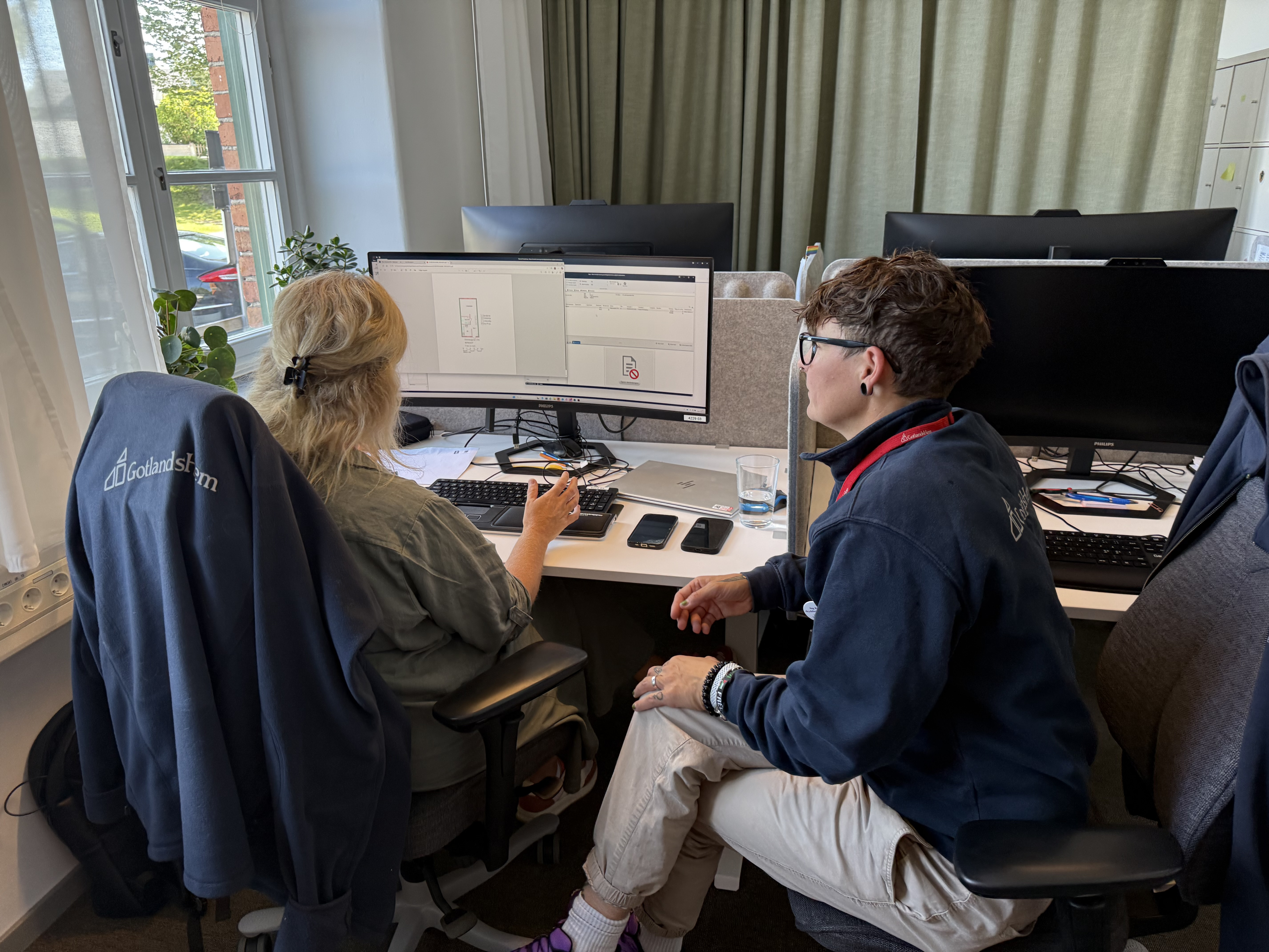 Två bostadsförmedlare sitter vid ett datorbord.