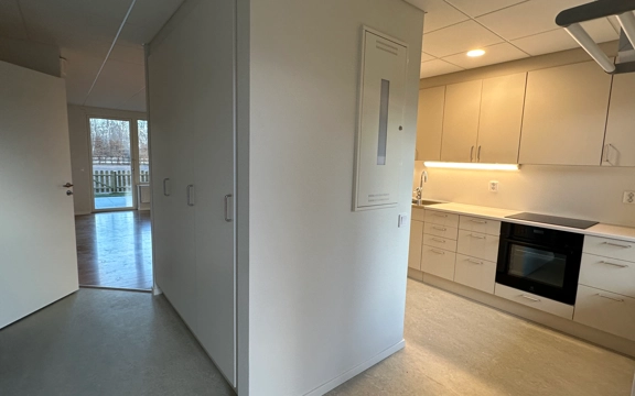 Visning av nybyggda bostäderna på Silvergatan, kvarteret Nötskrikan i Hemse. Flerfamiljshus i två våningar, gul fasad. Marken framför är bara tillplattad jord. Det är barmark men vinter. Klarblå himmel. 