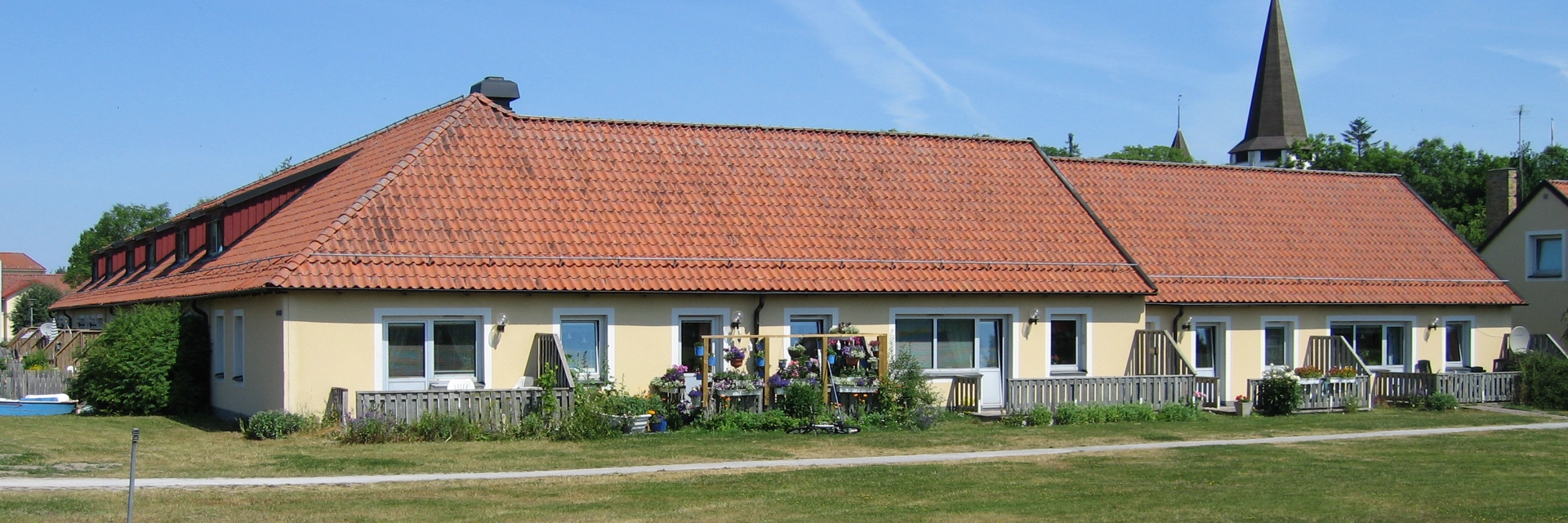 gult radhus med stort tak med röda tegelpannor.