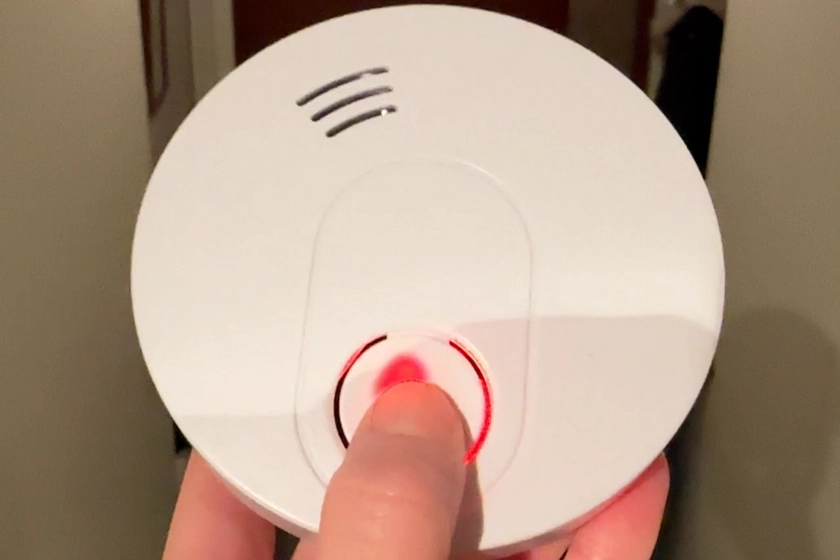 En person trycker på knappen på en brandvarnare.