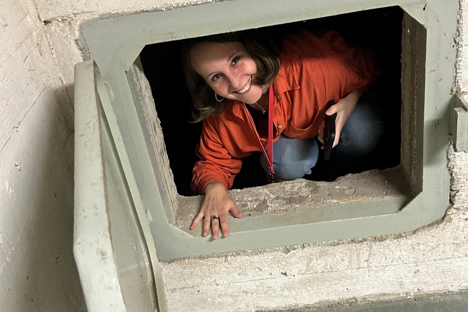 En kvinna kikar ut ur ett hål i en vägg.