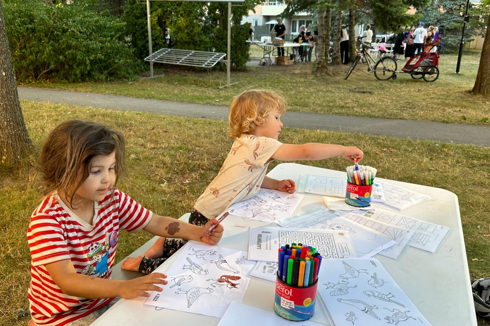Barn som ritar under en gemenskapsträff i kvarteret Vitkålens grönområde.