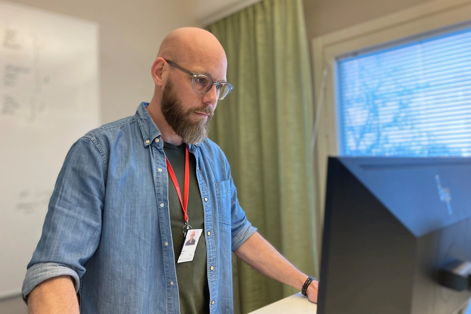 En man står och tittar koncentrerat på datorn.