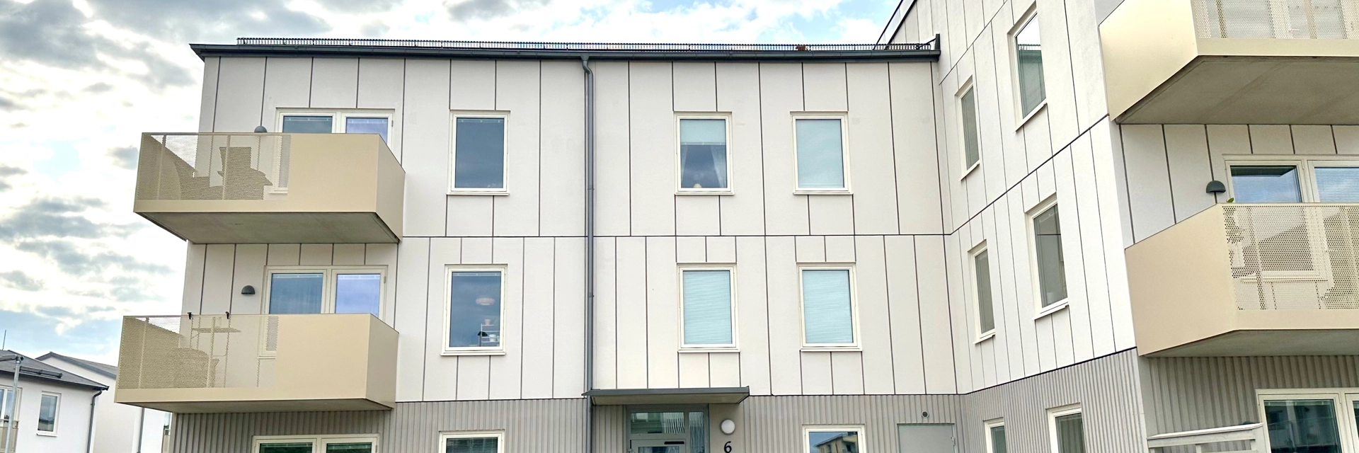 Fasad på Signallottan 2. Vit fasad och gula balkonger. 