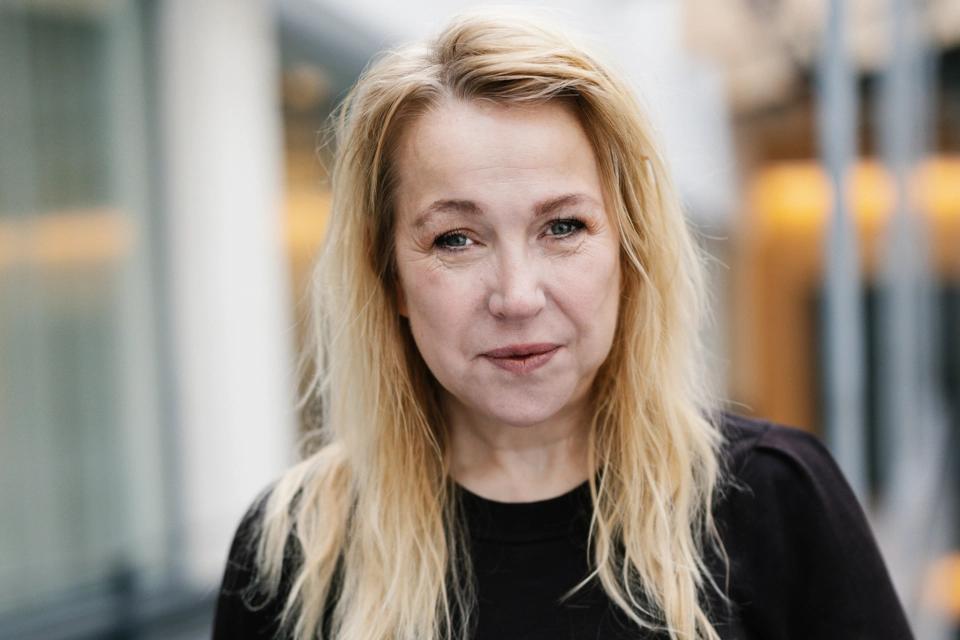 En kvinna står på en balkong intill en byggnad.
