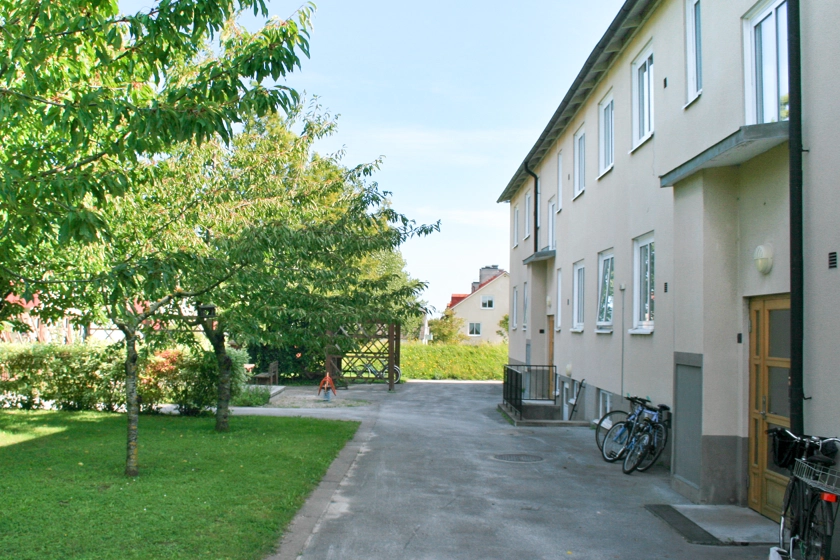 Ett flerbostadshus med grönskande gård.