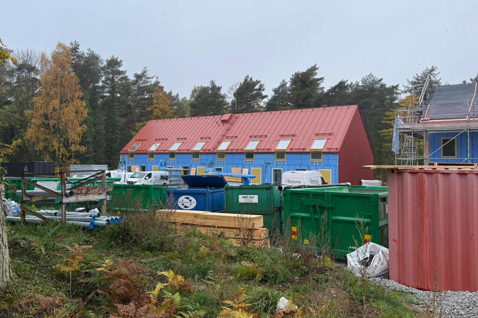 En grupp byggnader som ligger bredvid varandra. Ett nybyggt hus som nästan är klart syns på håll.