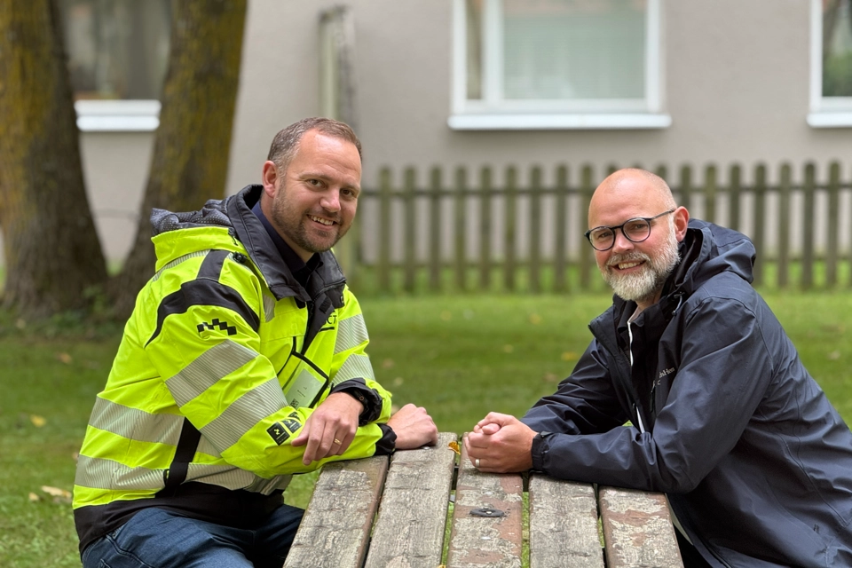 Två män som sitter vid ett bord framför ett hus.