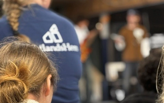 En grupp människor som sitter bredvid varandra. Man ser bara ryggen på alla.