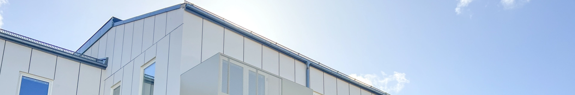 Flerbostadshus med vit fasad och gula balkonger. Klarblå himmel. 