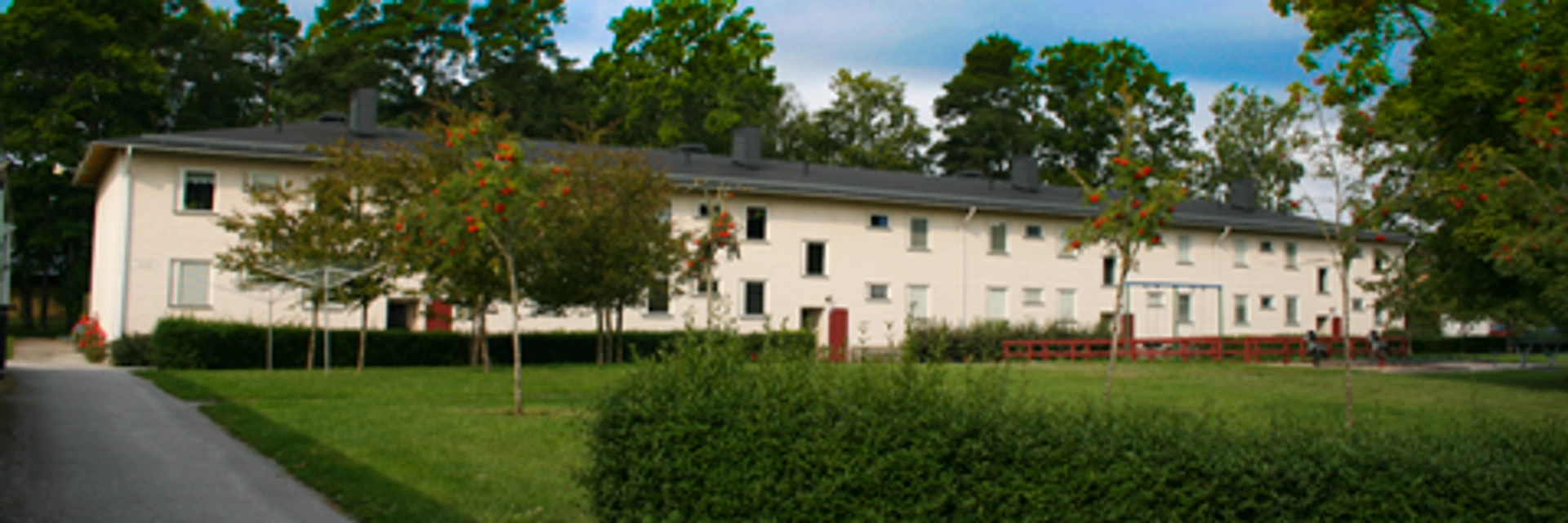 Vit radhuslänga med grönskande park framför